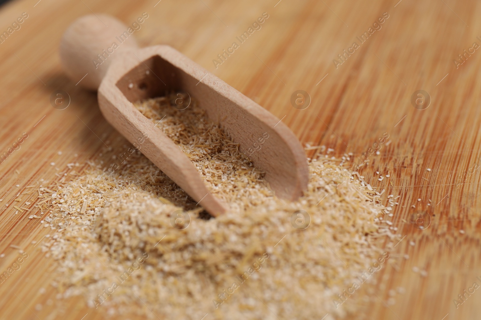 Photo of Oat bran in scoop on wooden table, closeup