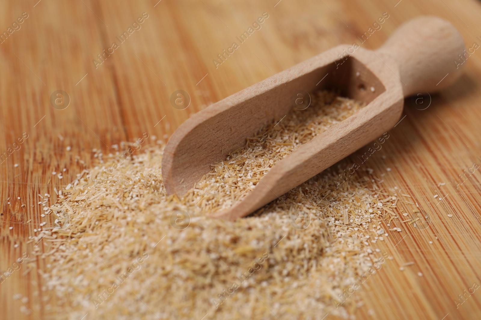 Photo of Oat bran in scoop on wooden table, closeup