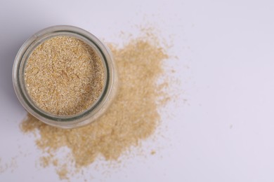 Photo of Oat bran in glass jar on white background, top view