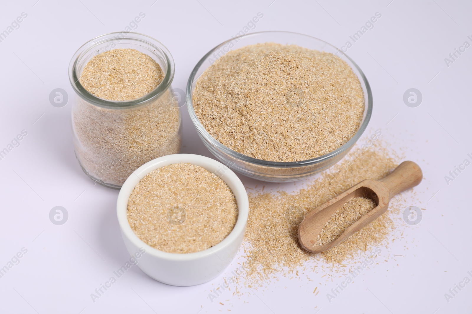 Photo of Oat bran in bowls, glass jar and wooden scoop on white background