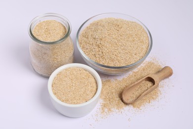 Photo of Oat bran in bowls, glass jar and wooden scoop on white background