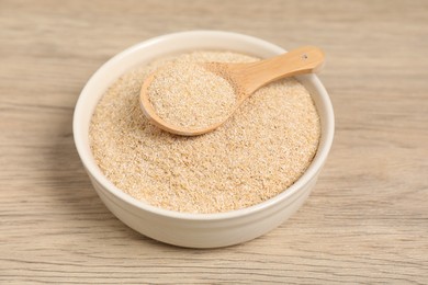 Photo of Oat bran in bowl and spoon on wooden table, closeup