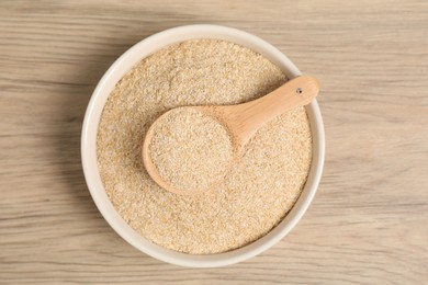 Photo of Oat bran in bowl and spoon on wooden table, top view