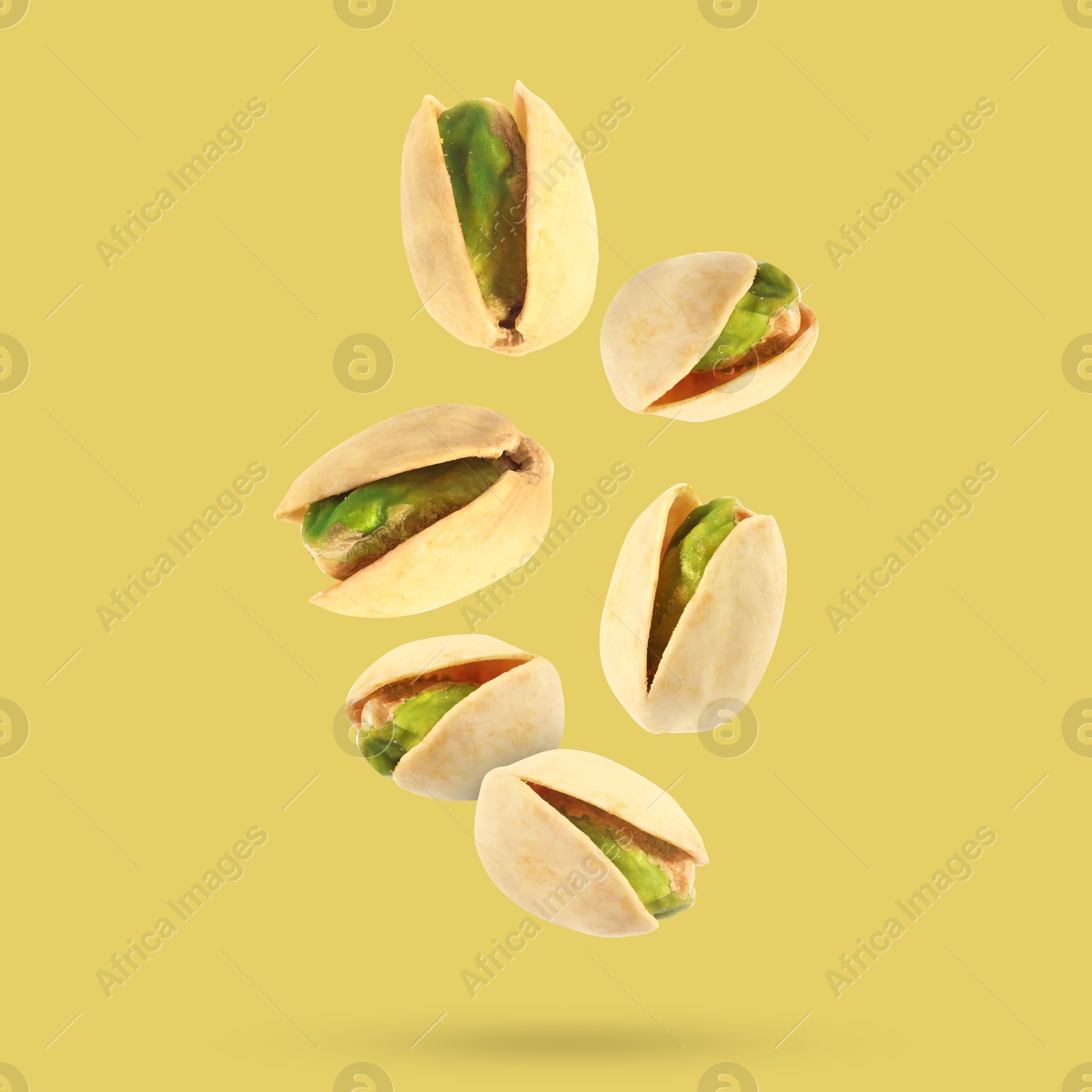 Image of Tasty pistachios in air on color background