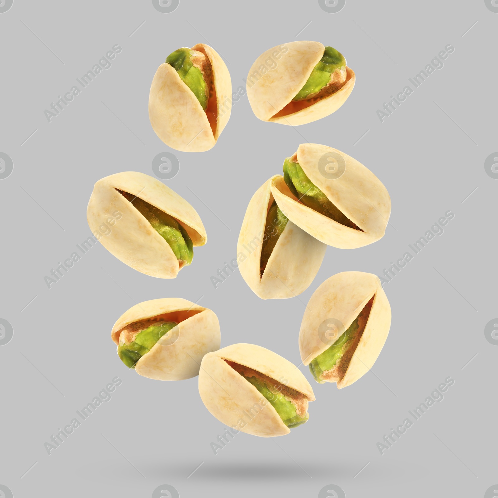 Image of Tasty pistachios falling on light grey background