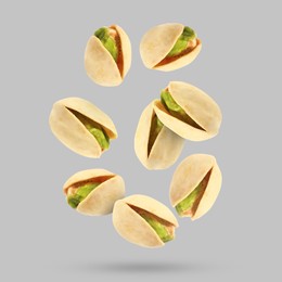 Image of Tasty pistachios falling on light grey background