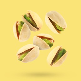 Image of Tasty pistachios in air on color background