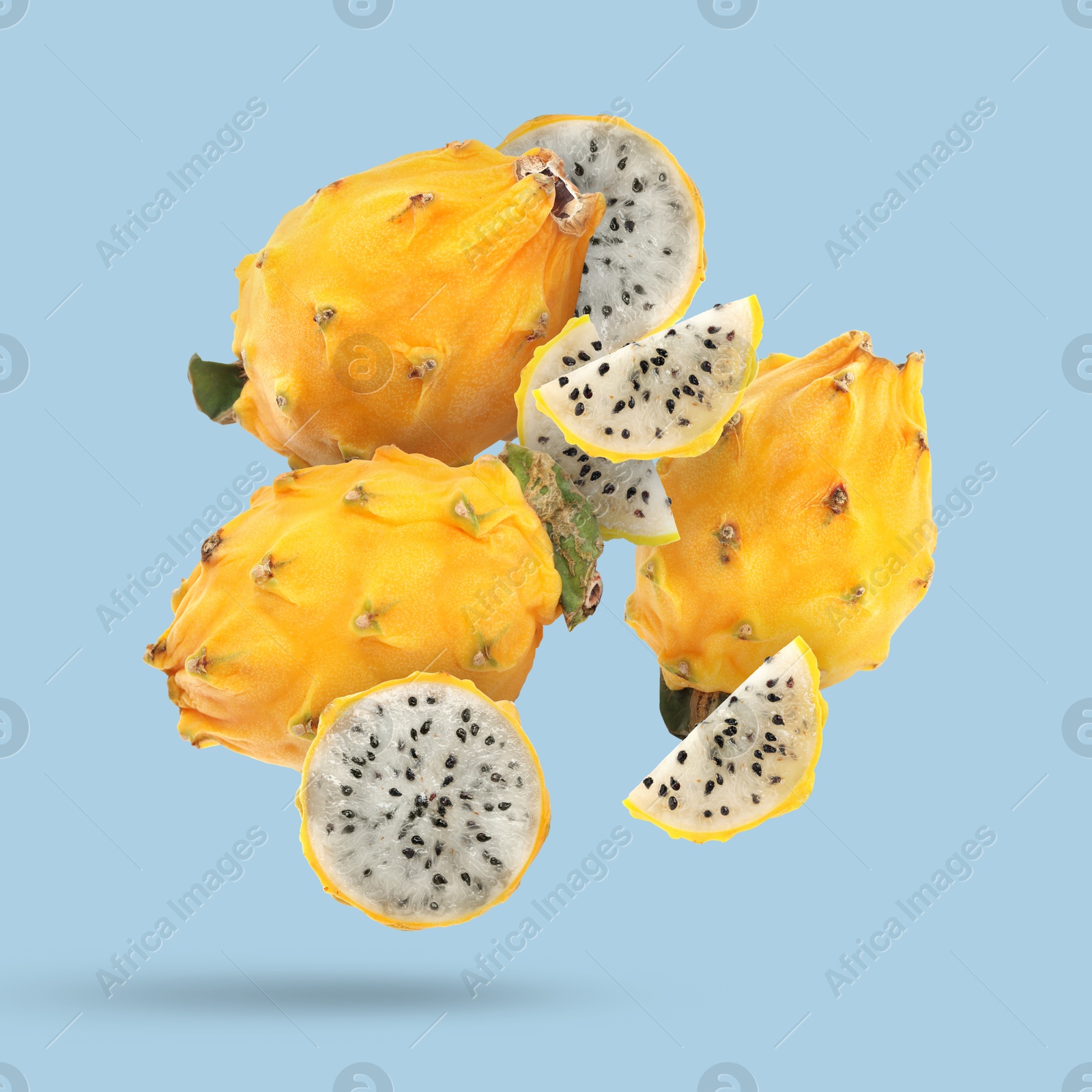 Image of Yummy yellow pitaya fruits falling on light blue background