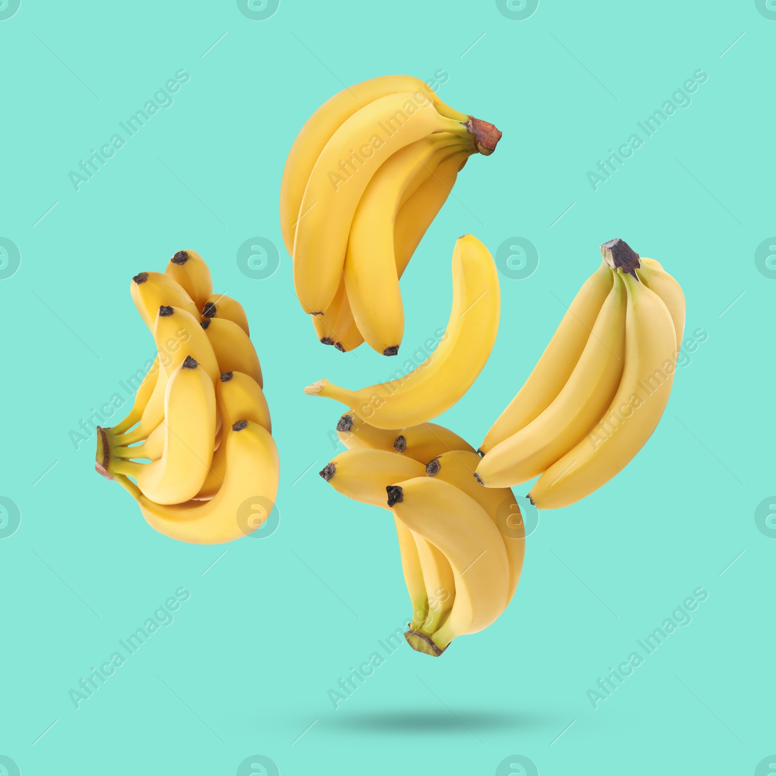 Image of Many yellow bananas falling on turquoise background