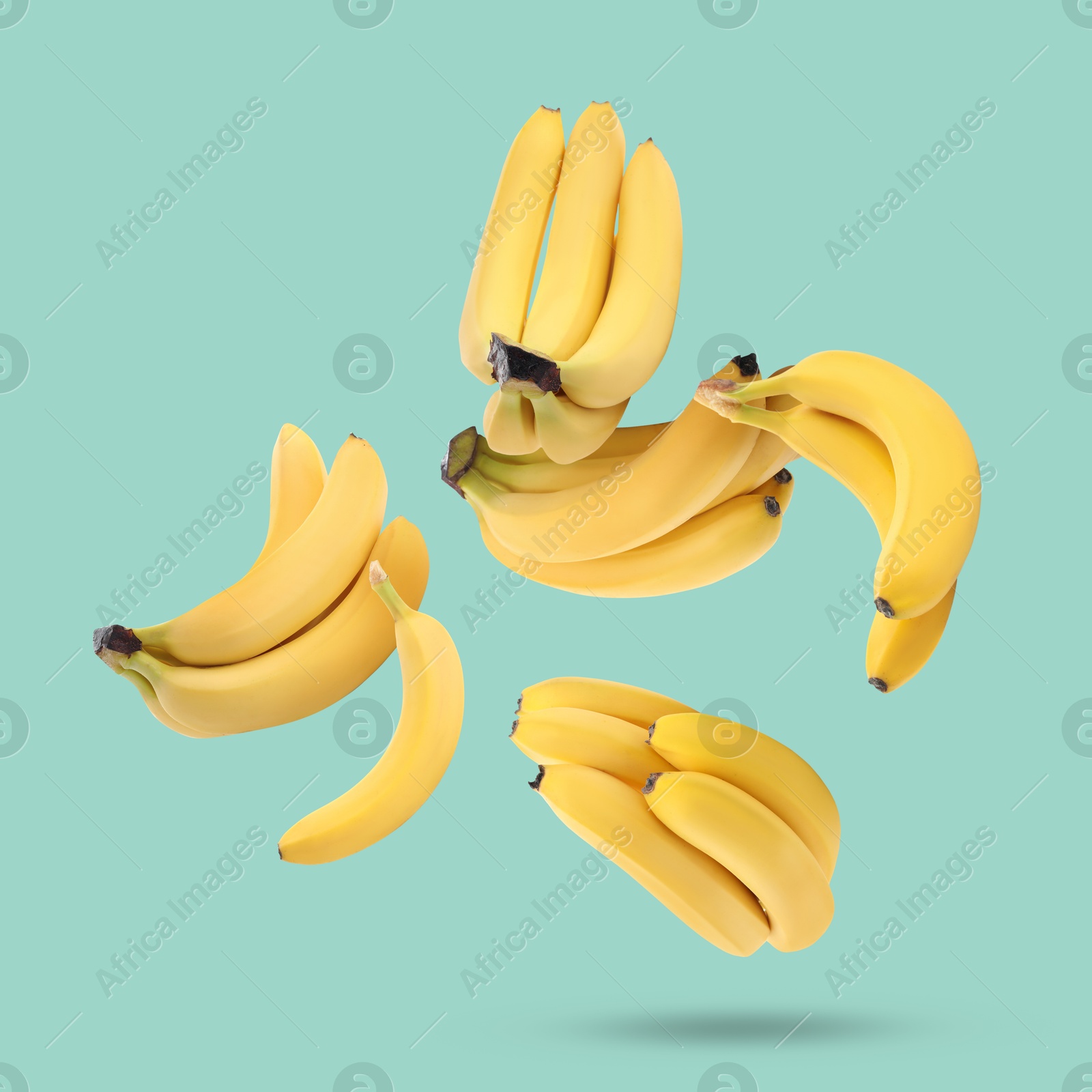 Image of Many yellow bananas falling on turquoise background