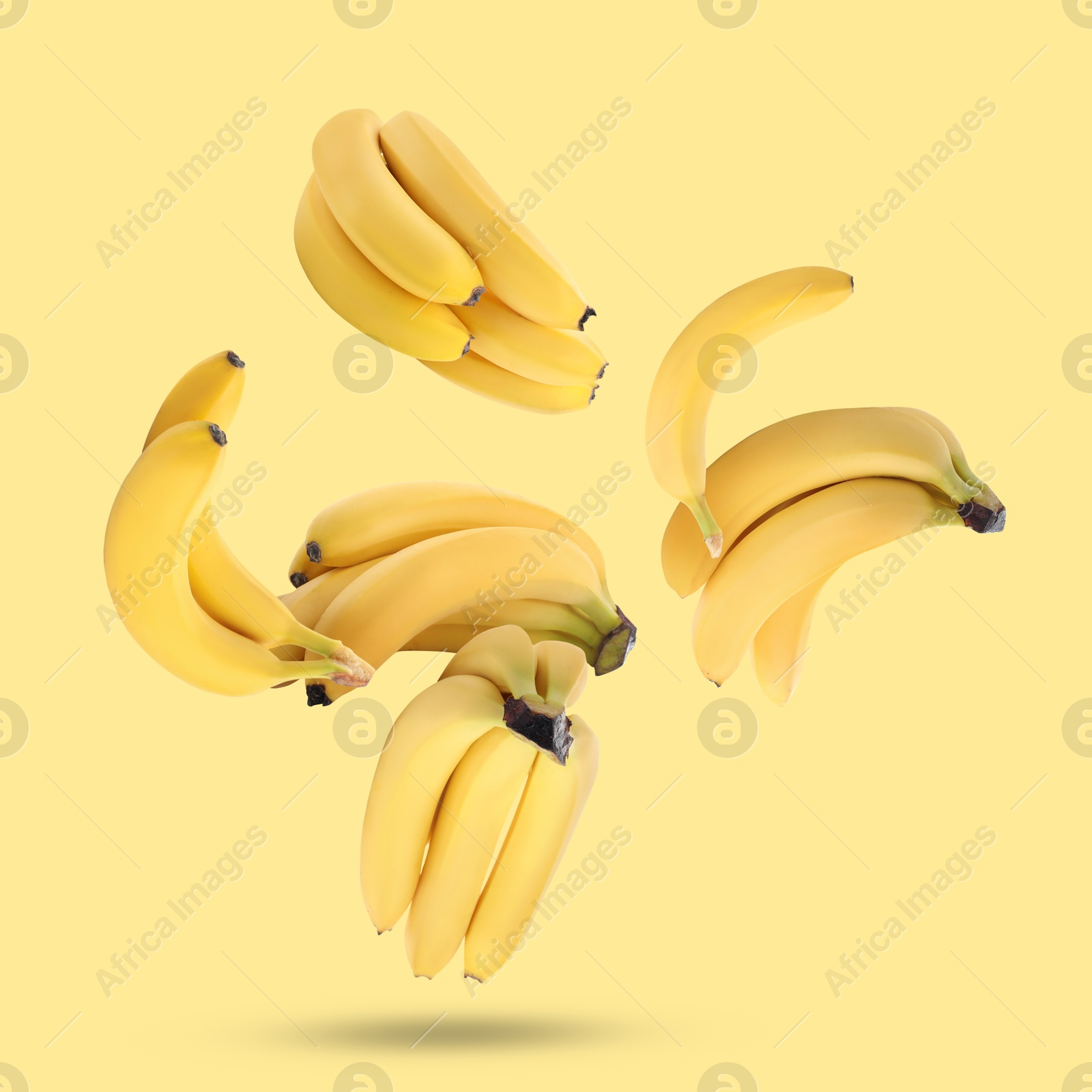 Image of Many fresh bananas falling on yellow background