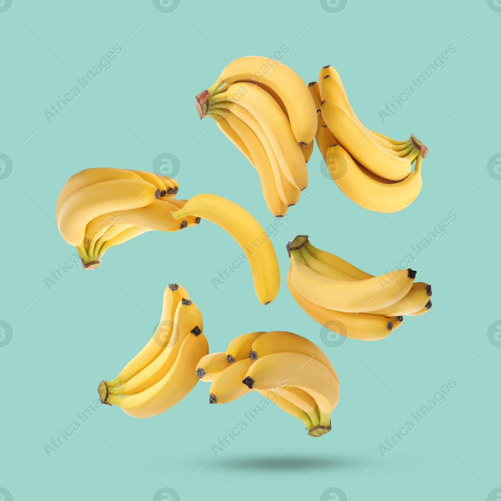 Image of Many yellow bananas falling on turquoise background