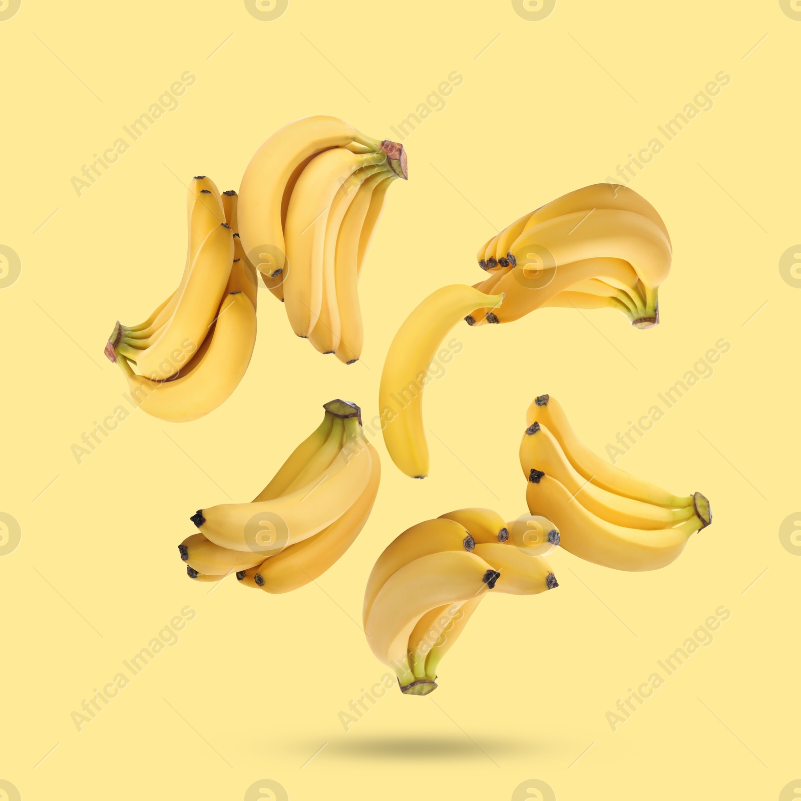 Image of Many fresh bananas falling on yellow background