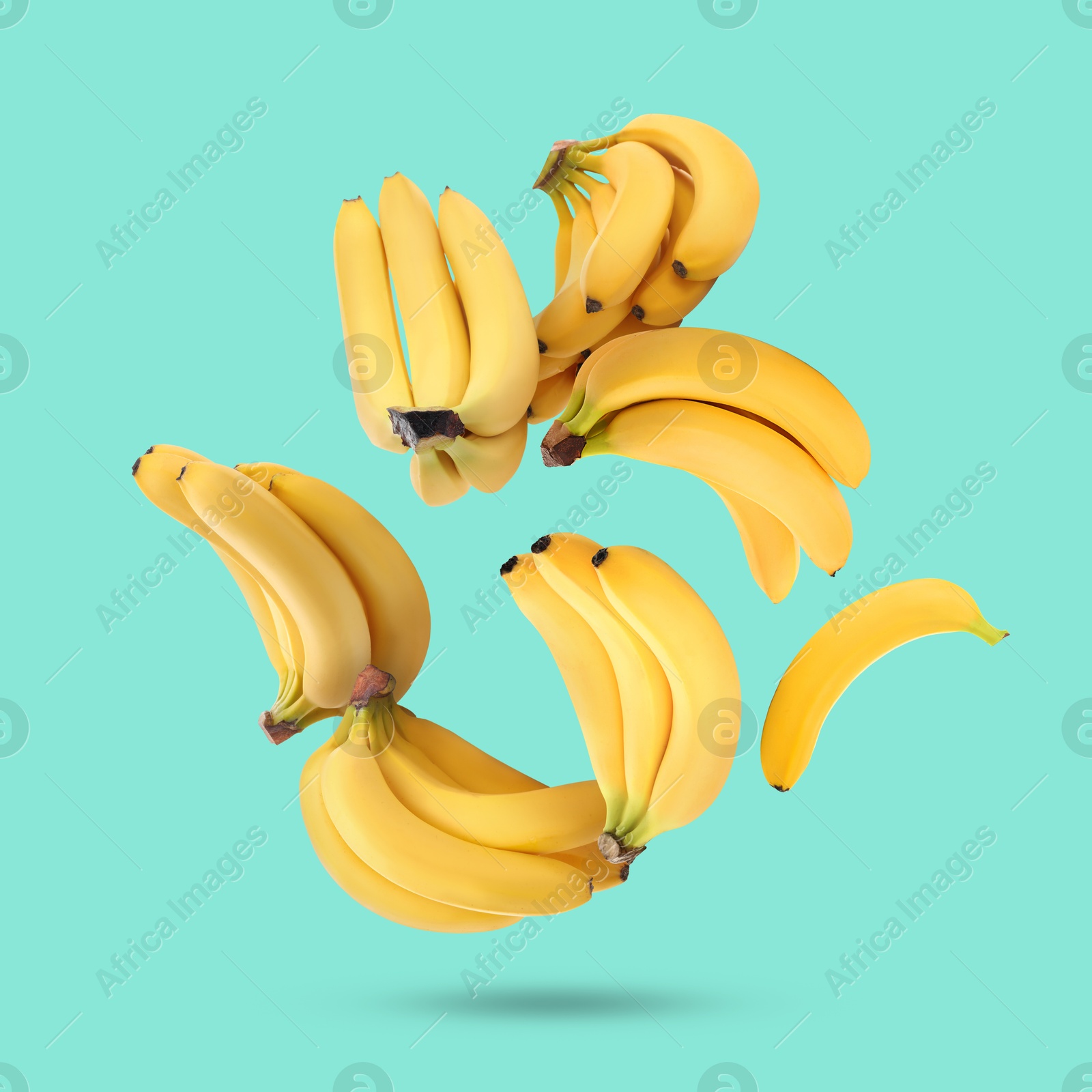 Image of Many yellow bananas falling on turquoise background