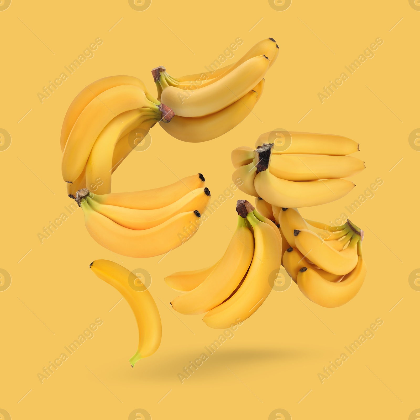 Image of Many fresh bananas falling on yellow background