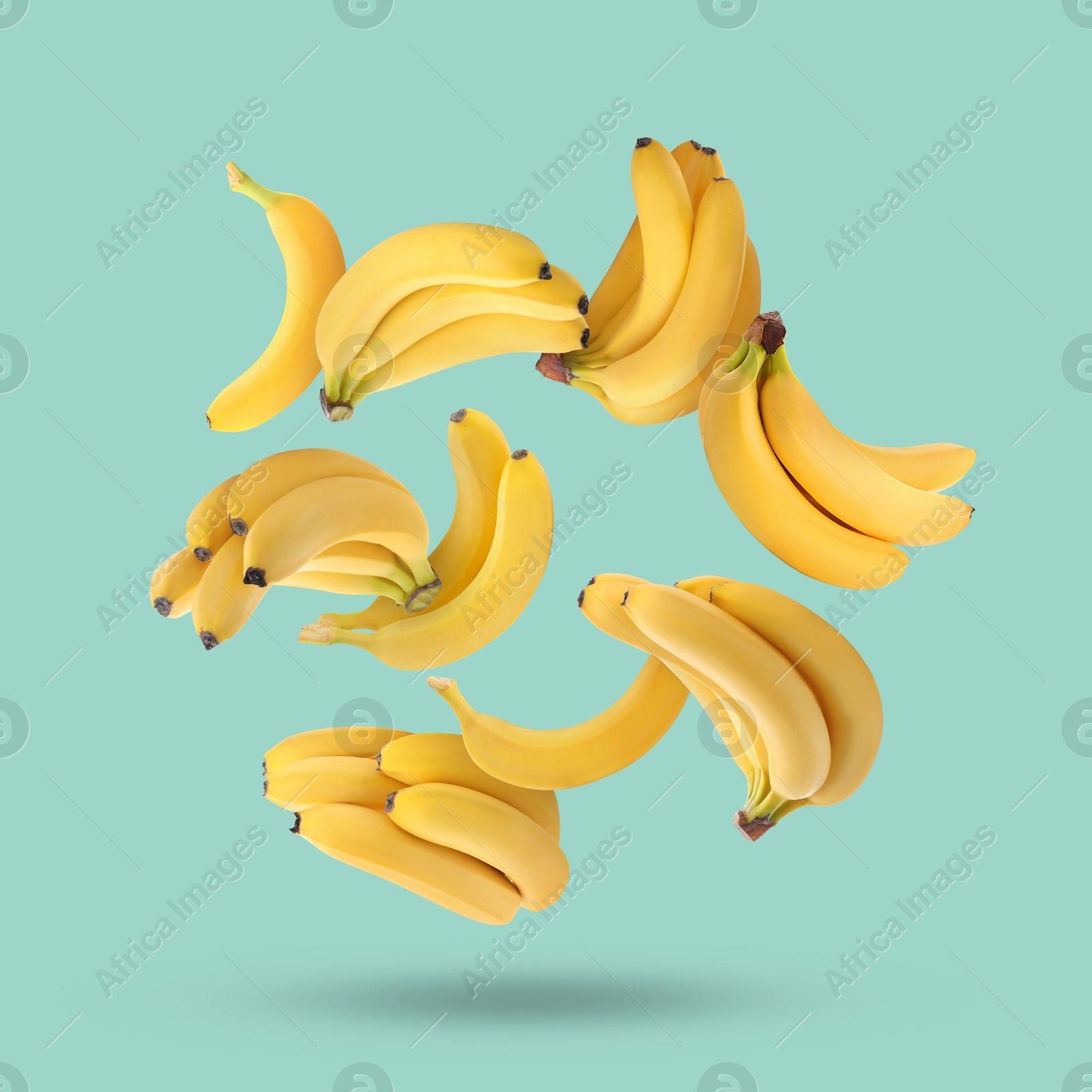 Image of Many yellow bananas falling on turquoise background