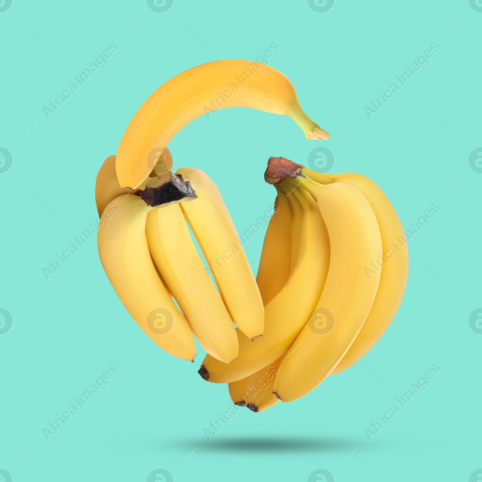 Image of Many yellow bananas falling on turquoise background