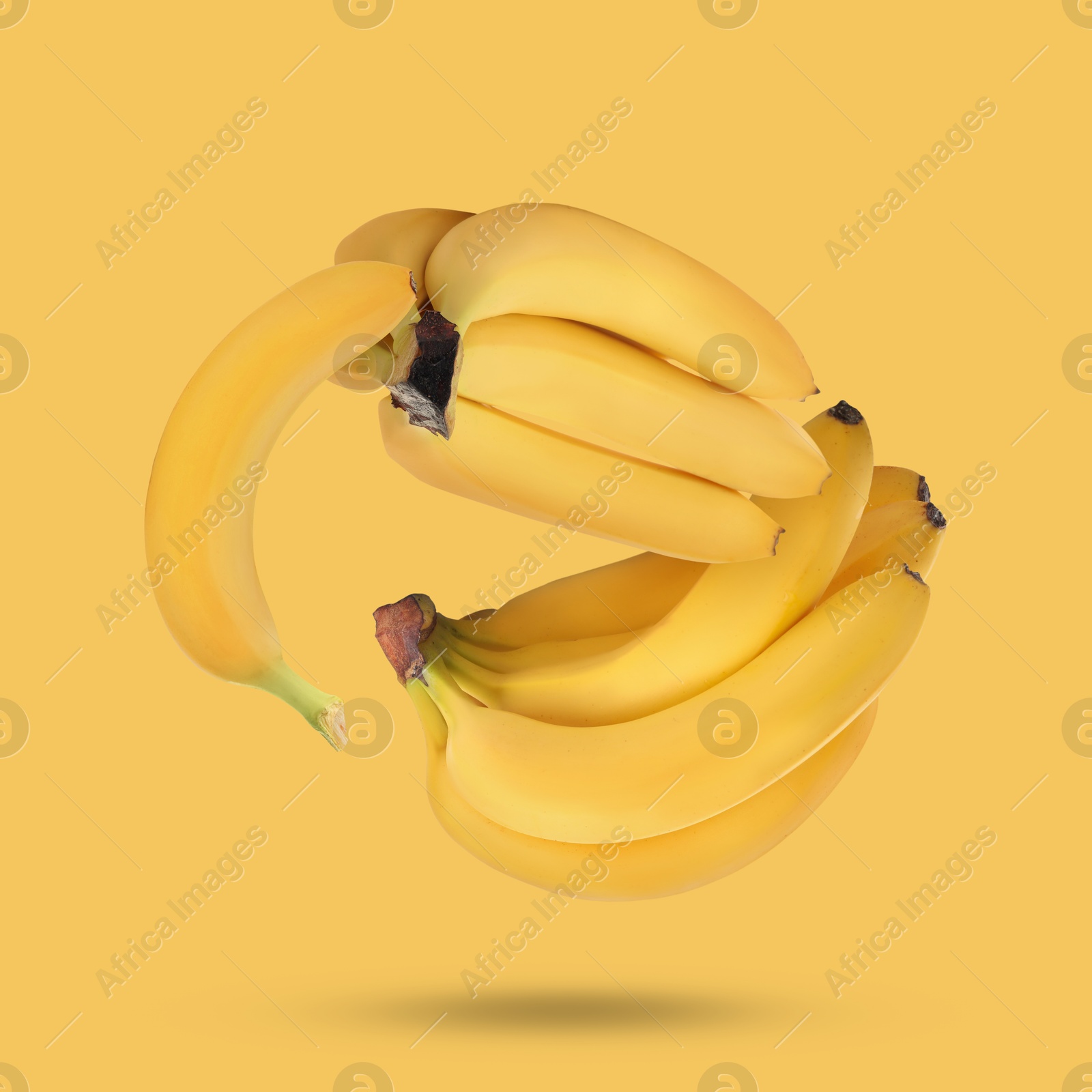 Image of Many fresh bananas falling on yellow background