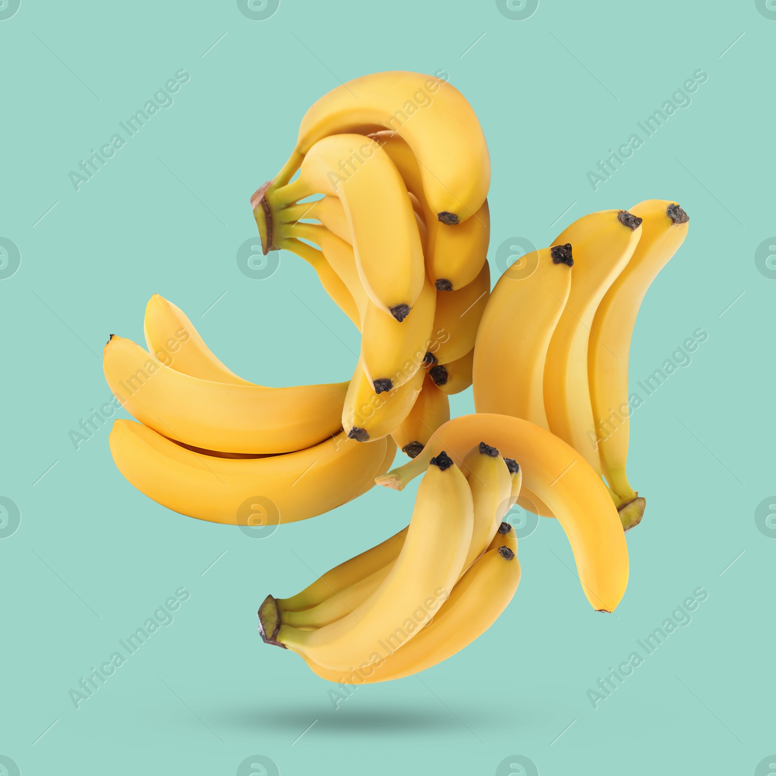 Image of Many yellow bananas falling on turquoise background