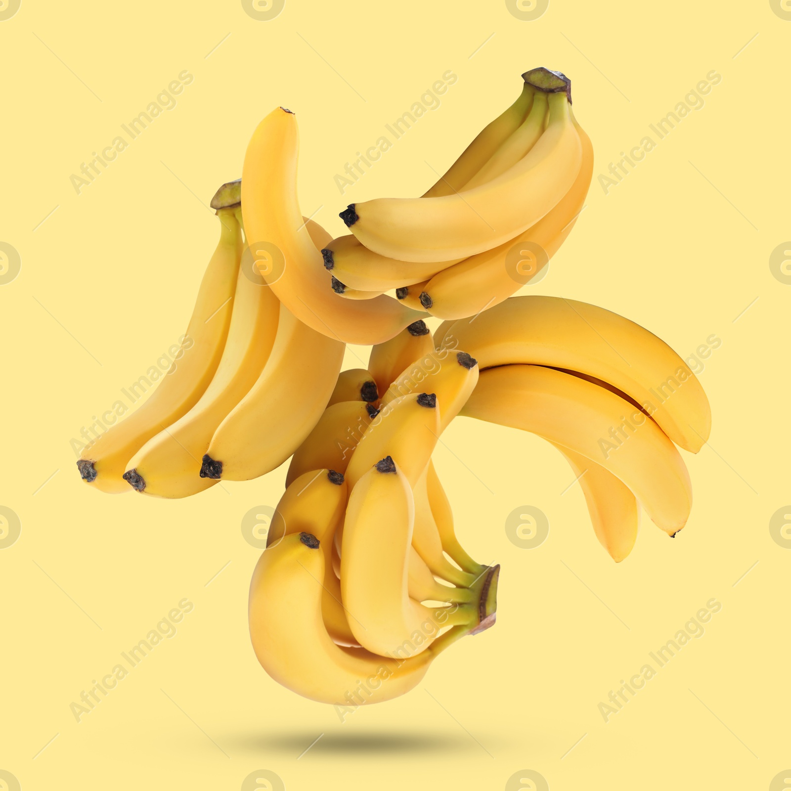 Image of Many fresh bananas falling on yellow background