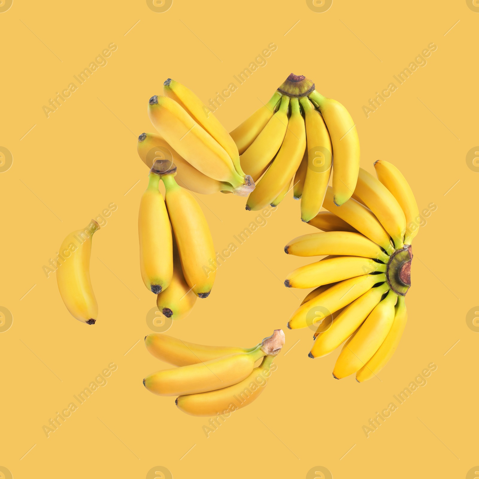 Image of Many fresh bananas falling on yellow background