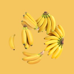 Image of Many fresh bananas falling on yellow background