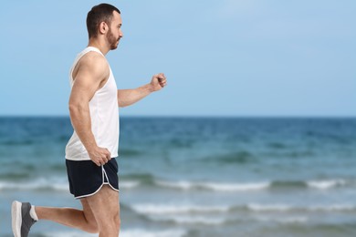 Image of Sporty man running on beach. Space for text