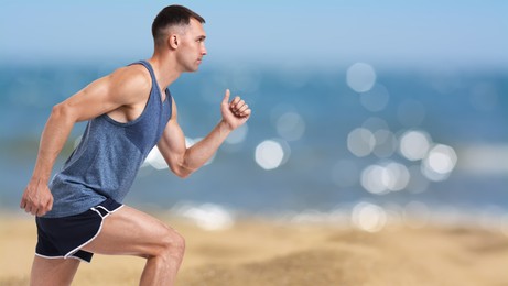 Image of Sporty man running on beach. Space for text