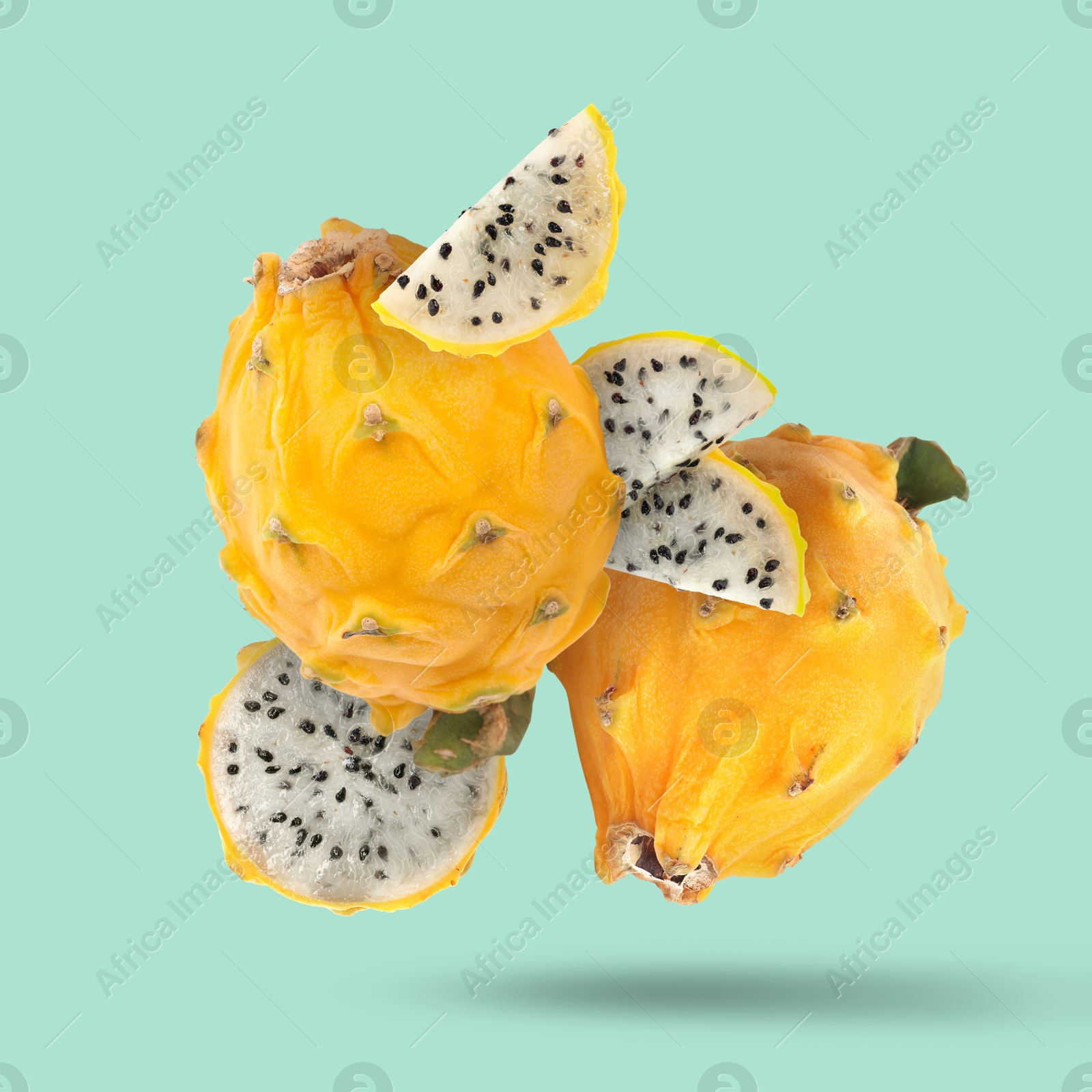 Image of Yummy yellow pitaya fruits falling on turquoise background