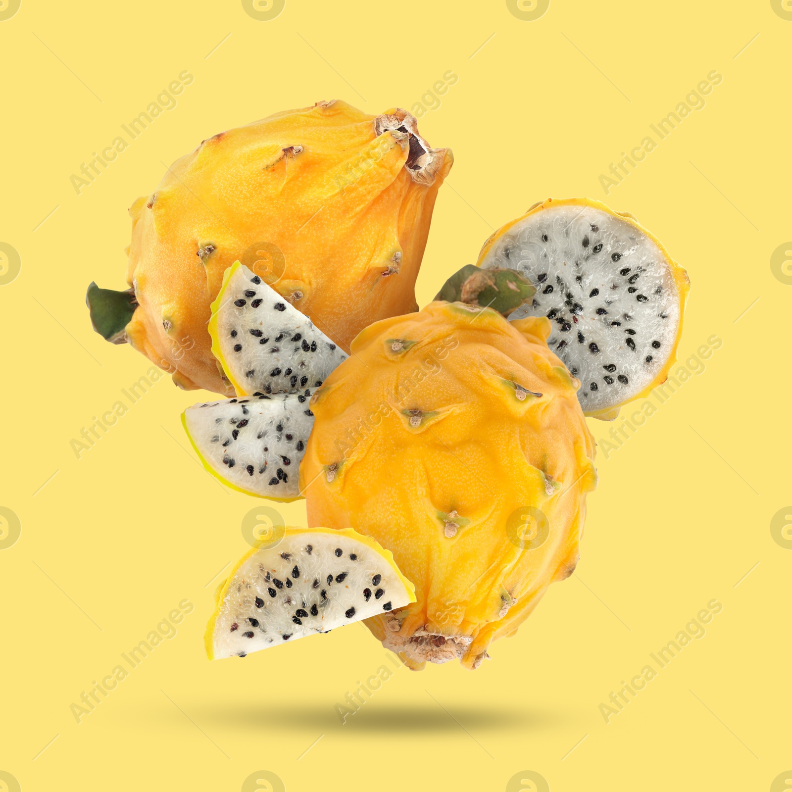 Image of Yummy pitaya fruits falling on yellow background