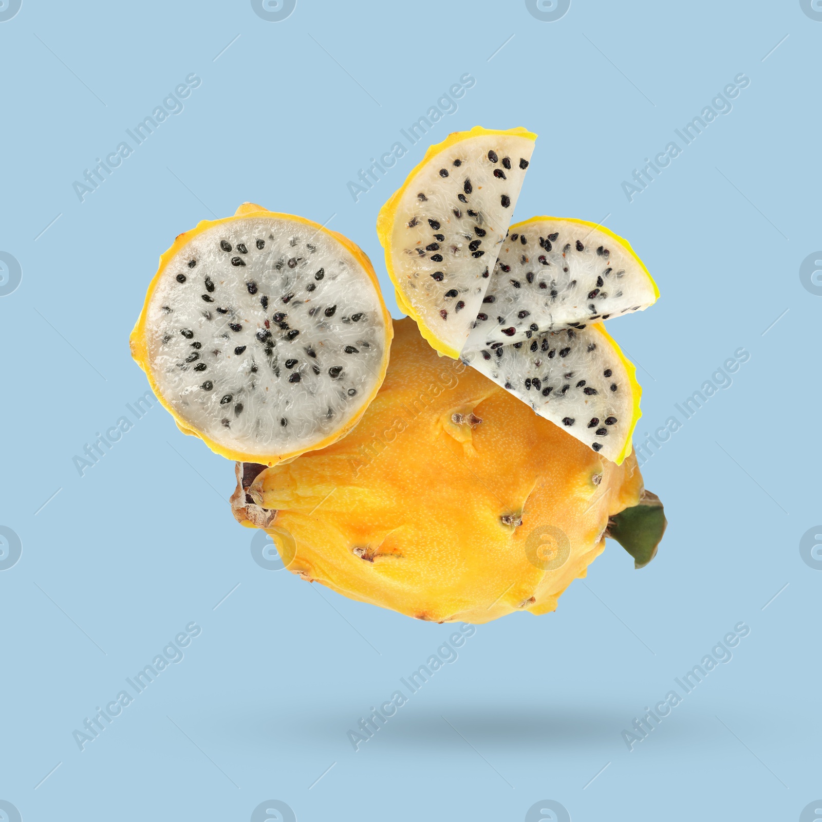 Image of Yummy yellow pitaya fruits falling on light blue background