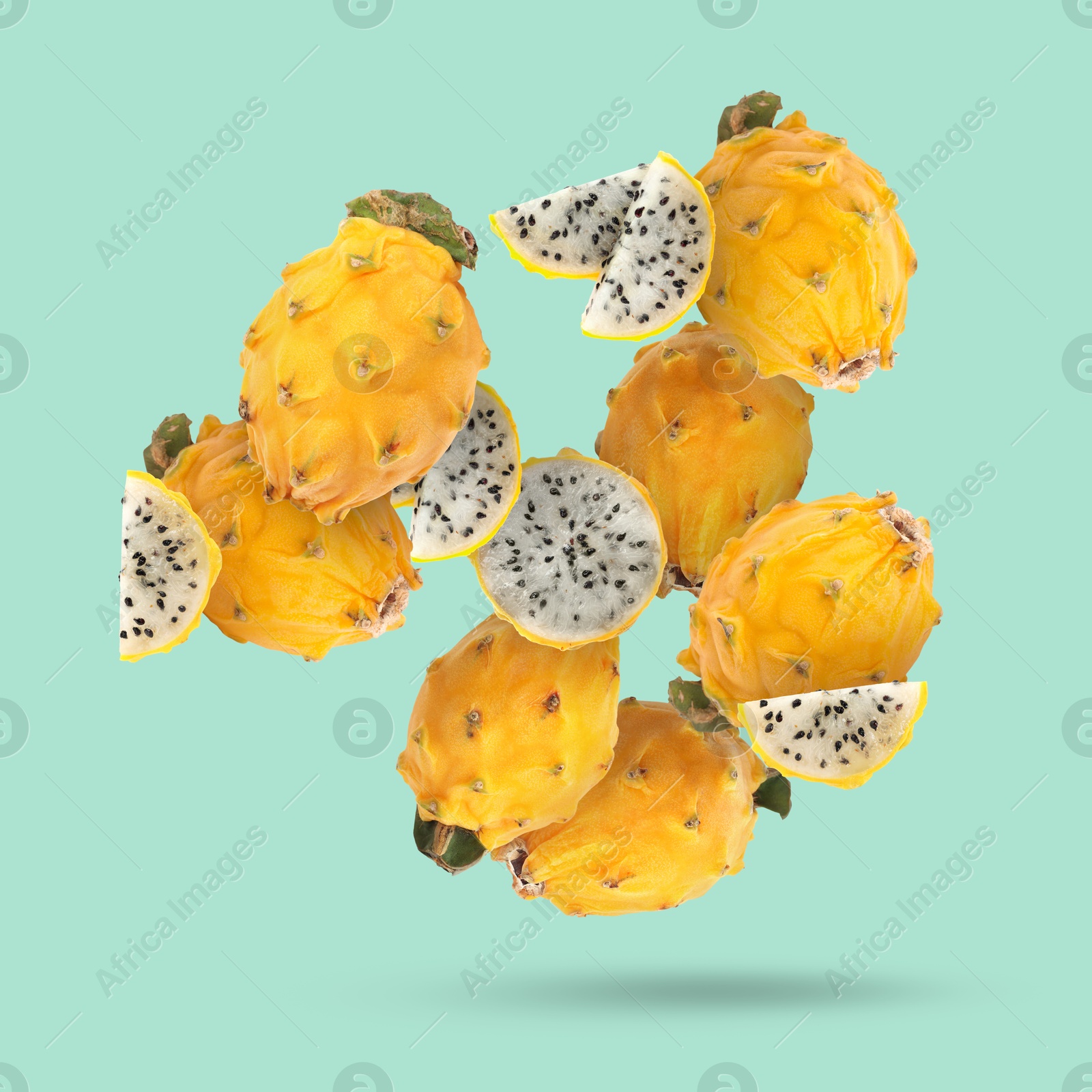 Image of Yummy yellow pitaya fruits falling on turquoise background