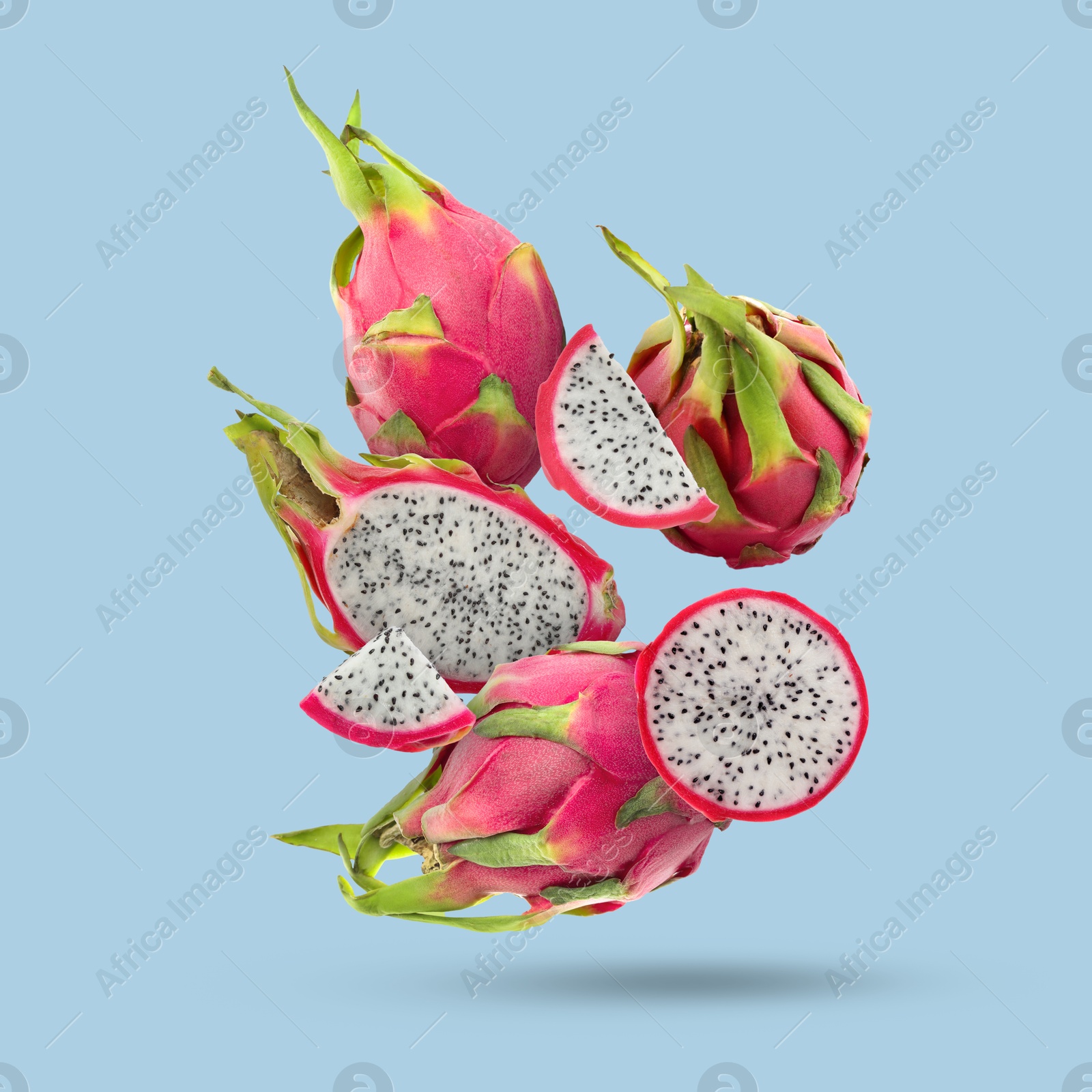 Image of Yummy pitaya fruits falling on light blue background