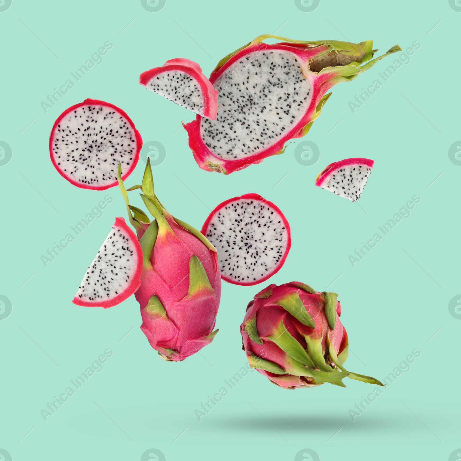 Image of Yummy pitaya fruits falling on turquoise background