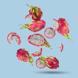 Image of Yummy pitaya fruits falling on light blue background