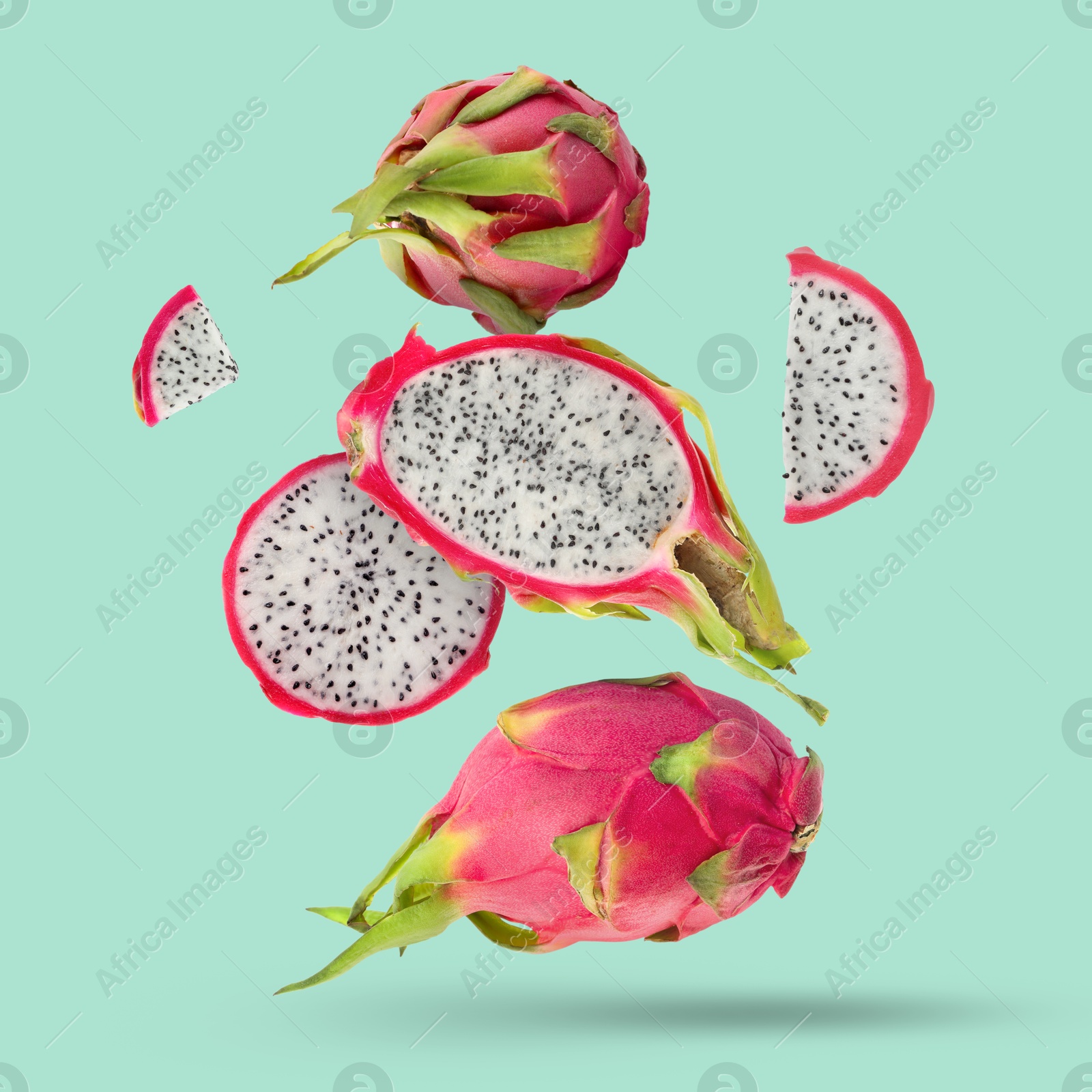 Image of Yummy pitaya fruits falling on turquoise background