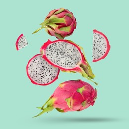 Image of Yummy pitaya fruits falling on turquoise background