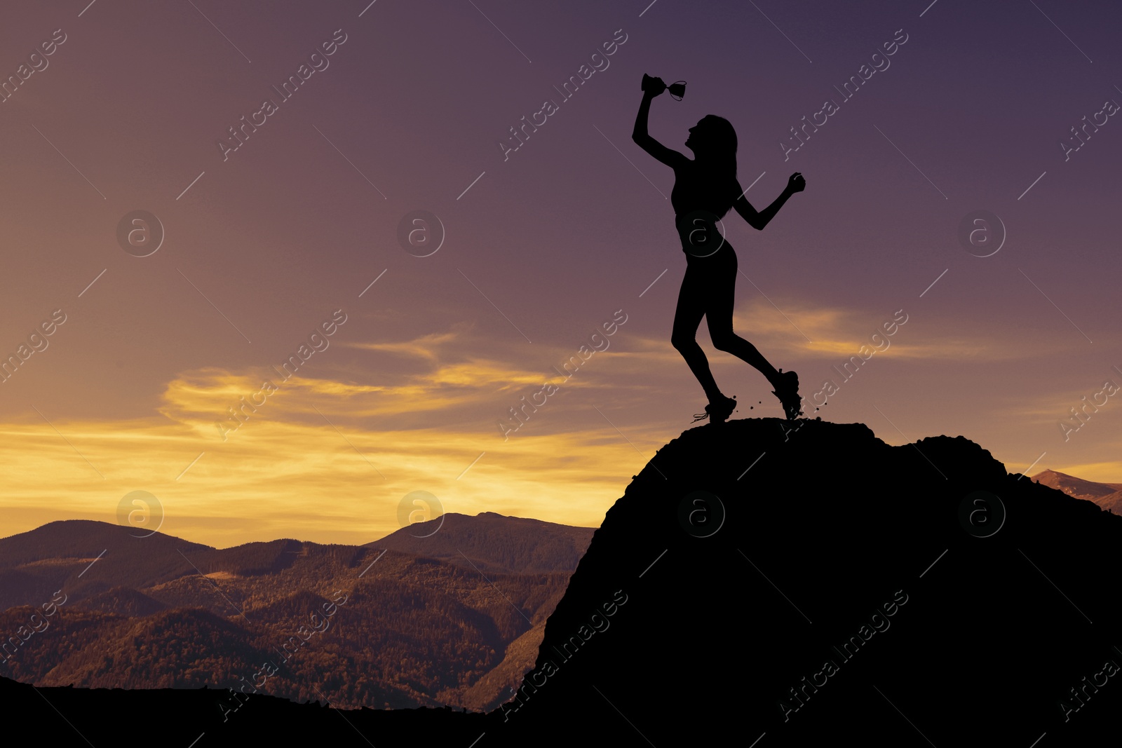 Image of Winner with trophy cup in mountains at sunrise