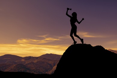 Winner with trophy cup in mountains at sunrise