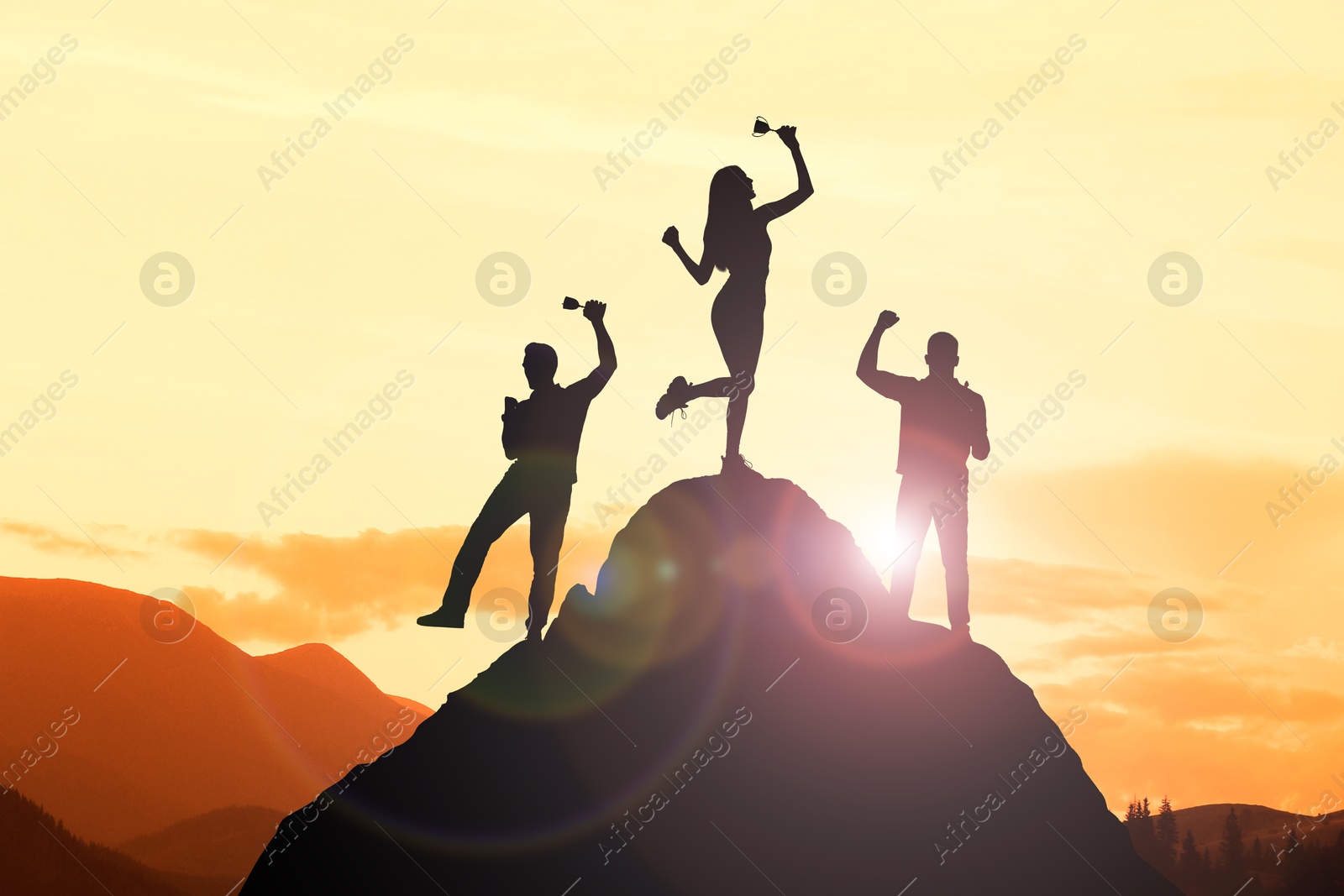 Image of Winners with trophy cups in mountains at sunrise