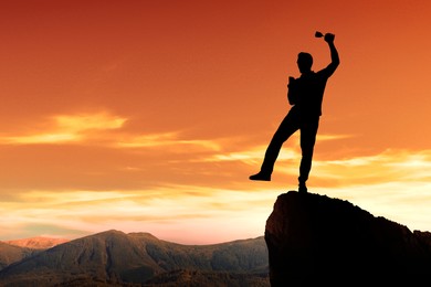 Image of Winner with trophy cup in mountains at sunrise