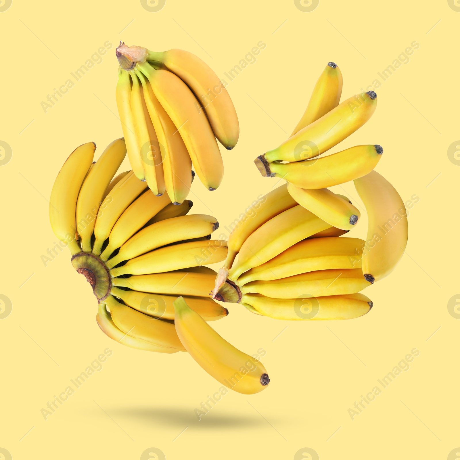 Image of Many fresh bananas falling on yellow background