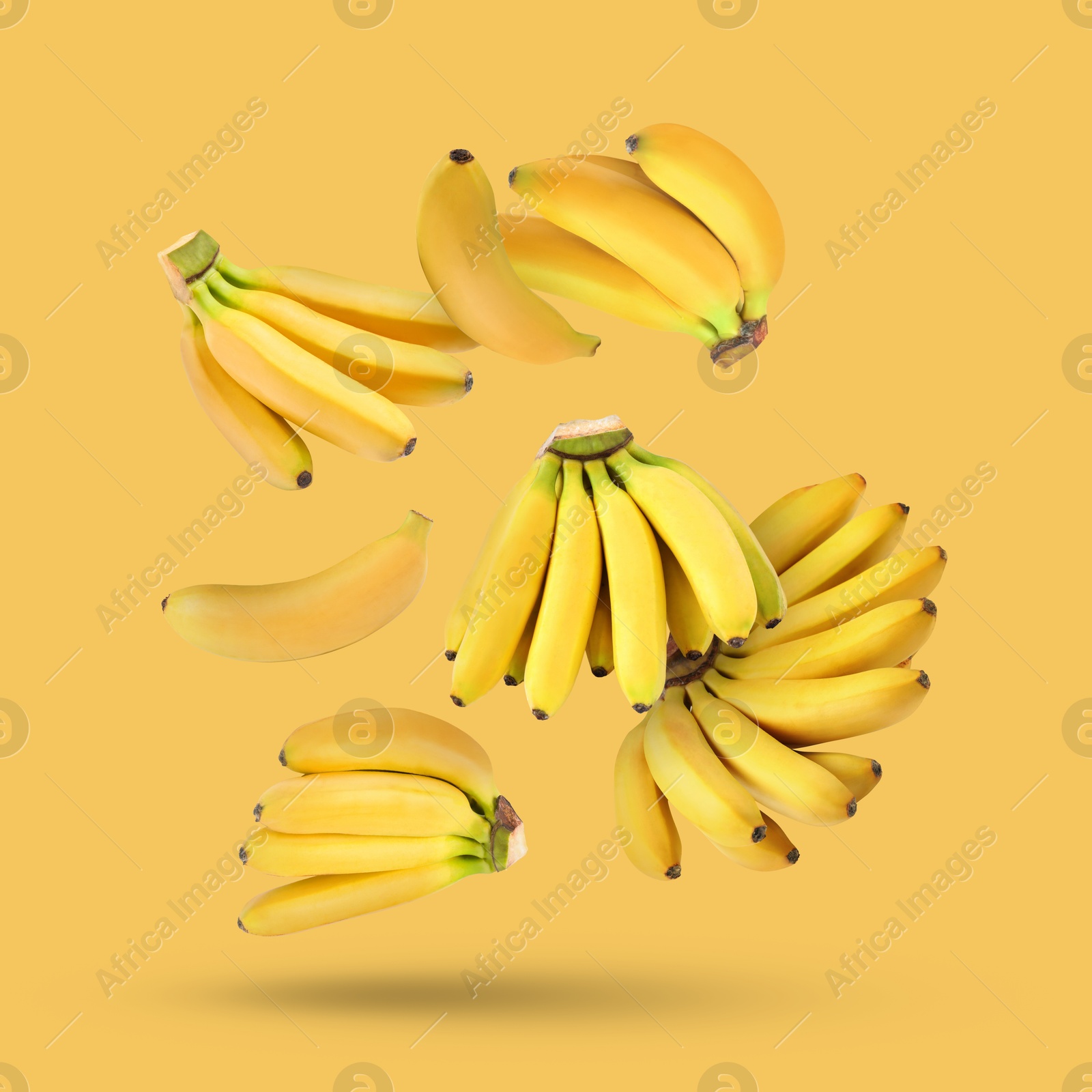 Image of Many fresh bananas falling on yellow background