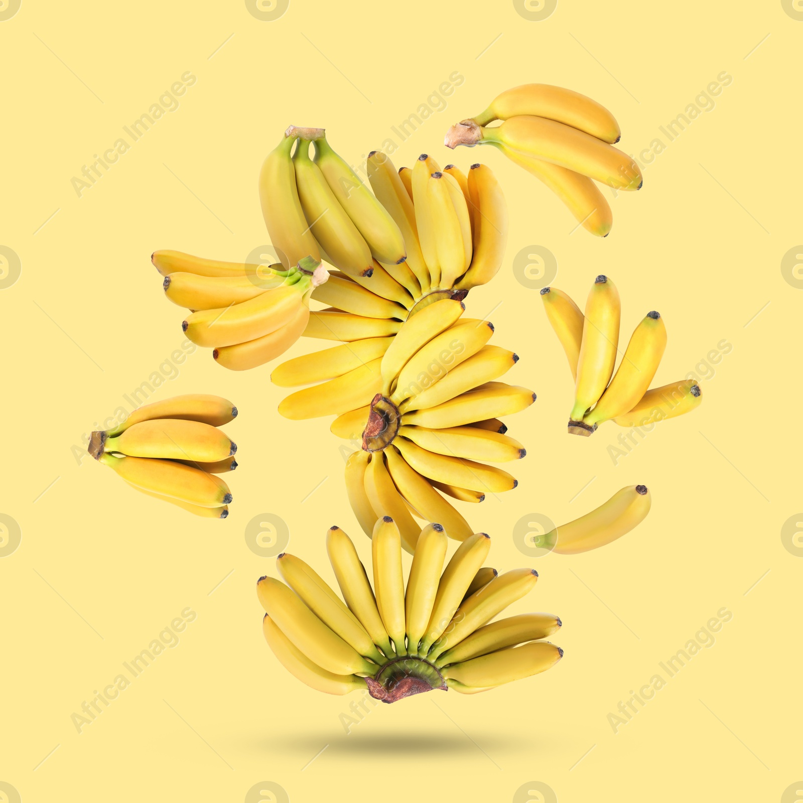 Image of Many fresh bananas falling on yellow background