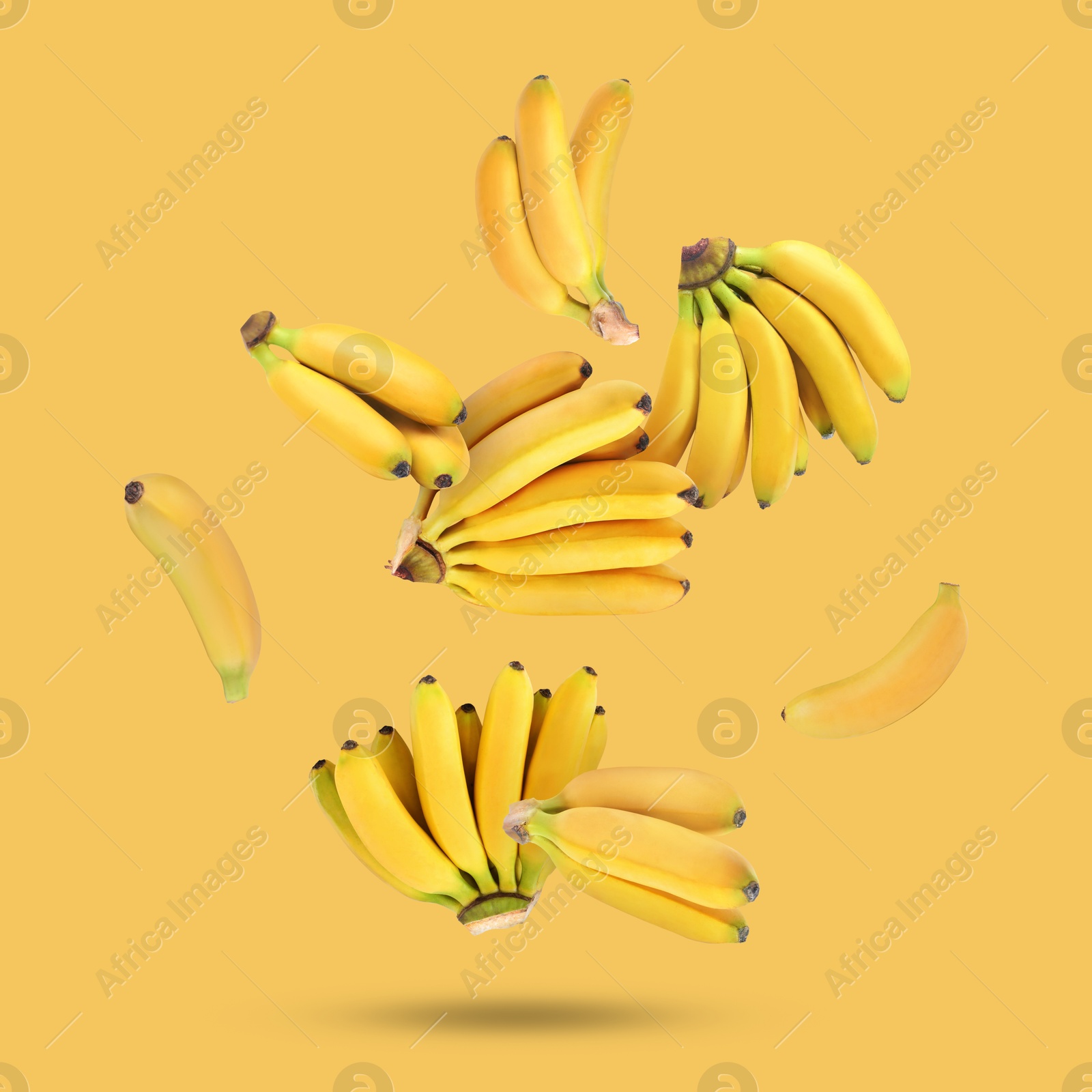 Image of Many fresh bananas falling on yellow background