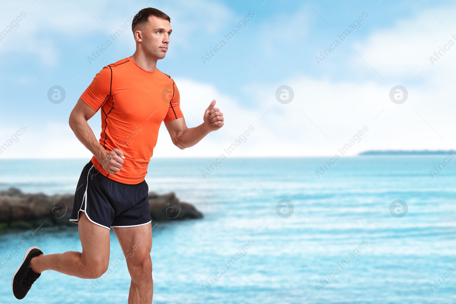 Image of Sporty man running on beach. Space for text