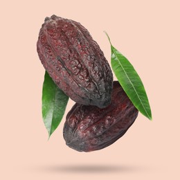 Cocoa pods and green leaves in air on peach color background