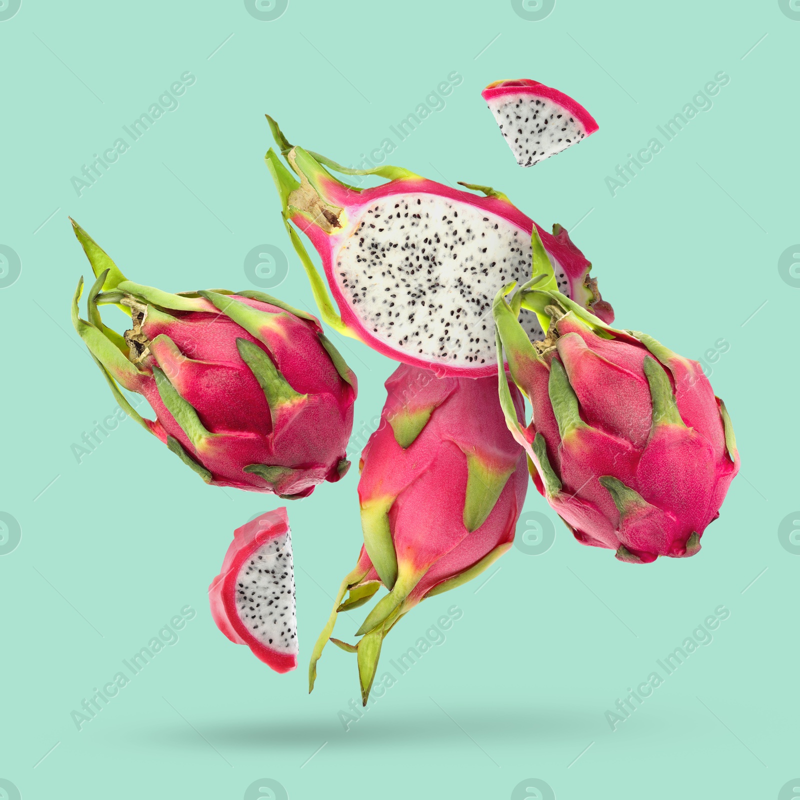 Image of Yummy pitaya fruits falling on turquoise background