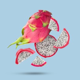 Image of Yummy pitaya fruits falling on light blue background