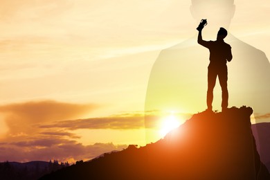 Winner with trophy cup in mountains at sunrise and silhouette of man